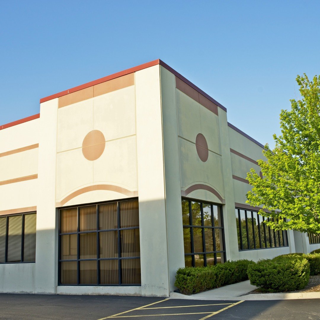 Freshly painted commercial building, tan and white, with a green tree in the foreground.