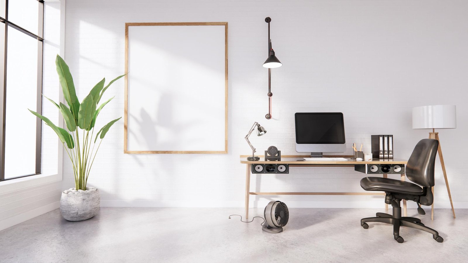 A modern desk with a computer, speakers, and a lamp.