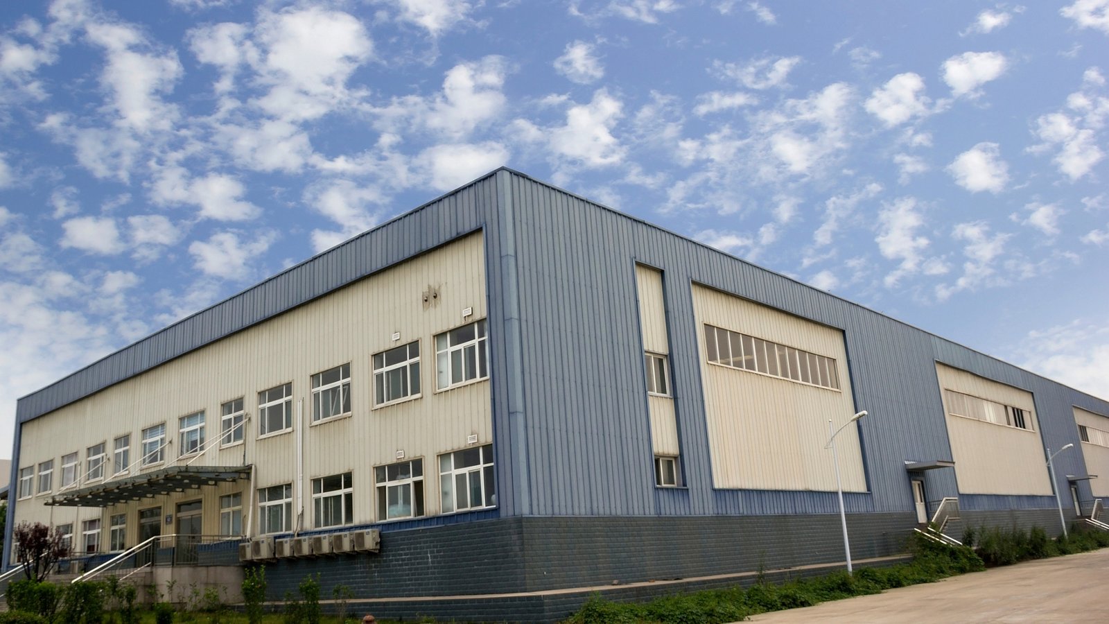 Freshly painted grey warehouse, surrounded by a security fence.