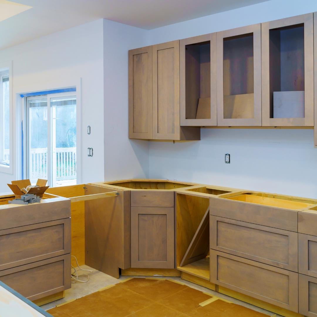 Image of new granite countertops being installed in a kitchen with white cabinets and a sink.