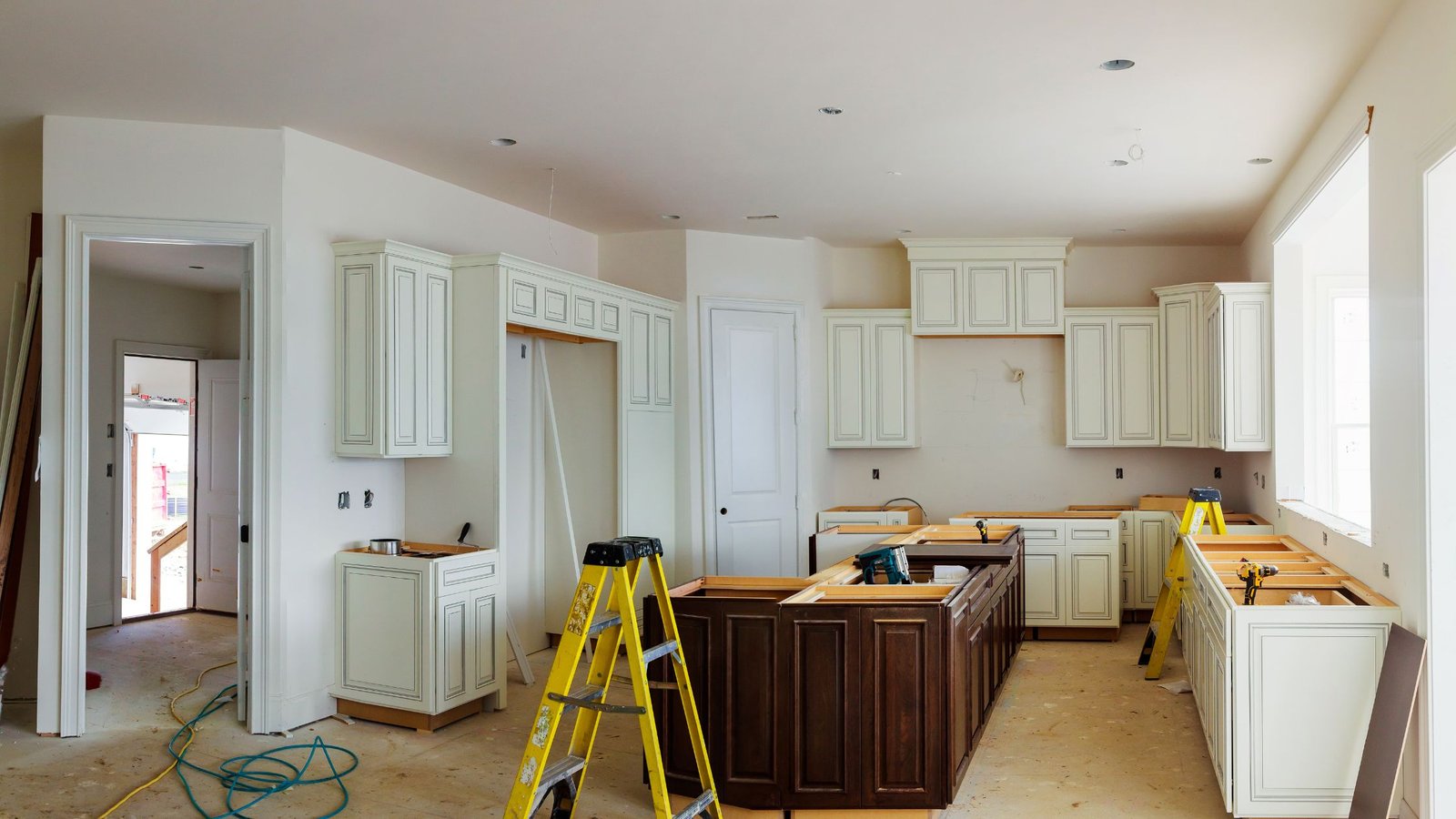 A completely remodeled kitchen with new white cabinets, quartz countertops, stainless steel appliances, and a mosaic tile backsplash.