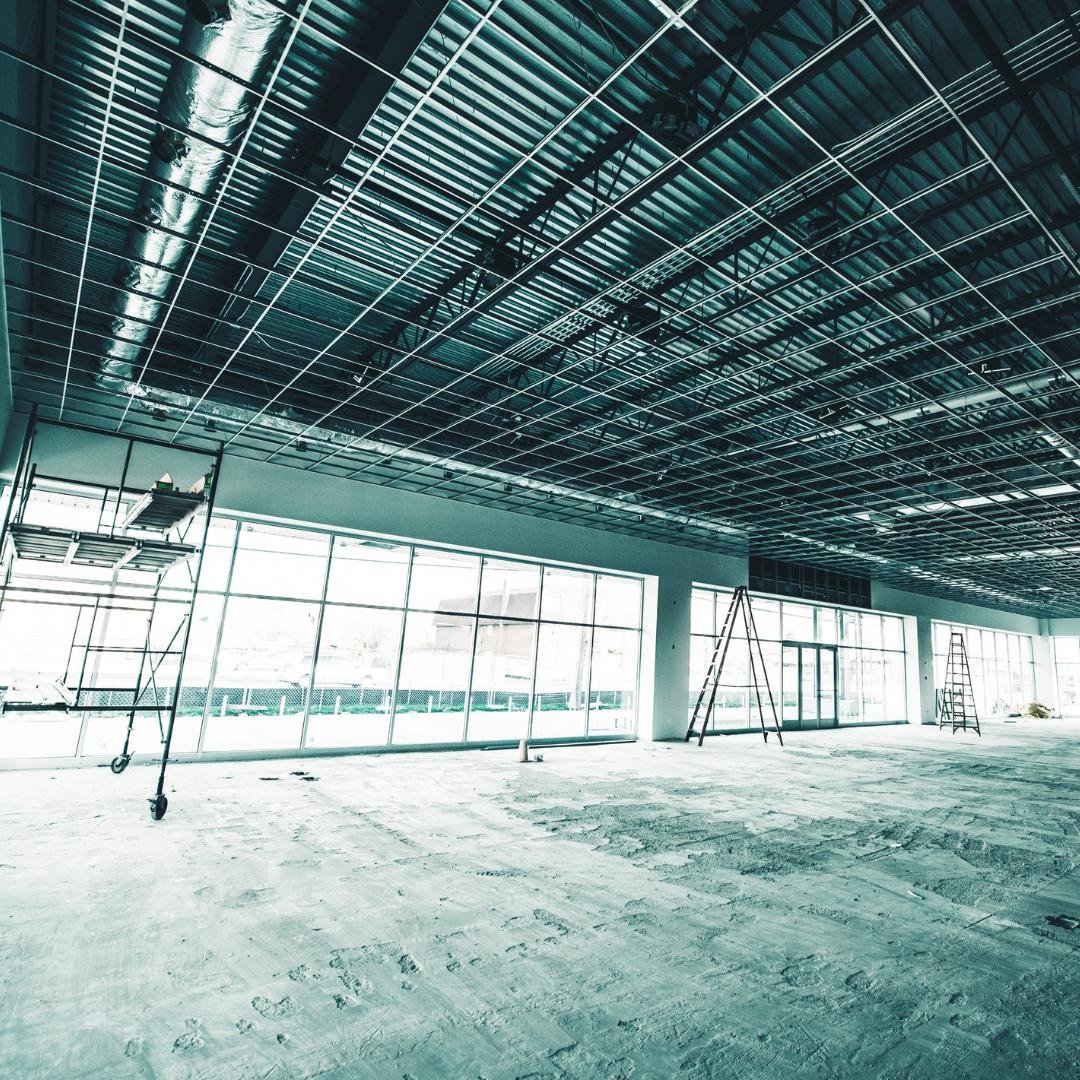 Commercial building space in the middle of a remodel. Pipes exposed and scaffolding on the left.