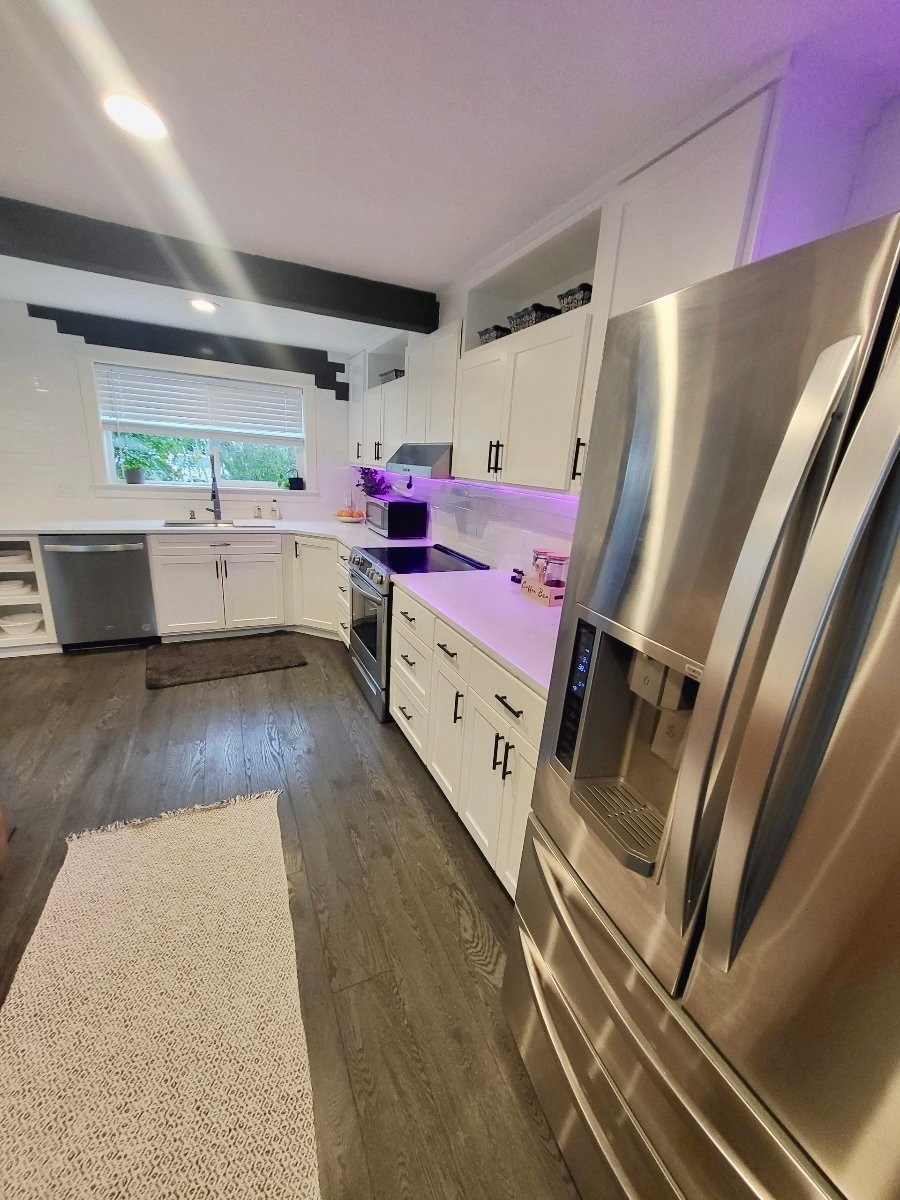 Modern remodeled kitchen with white cabinets, stainless steel appliances, and granite countertops.