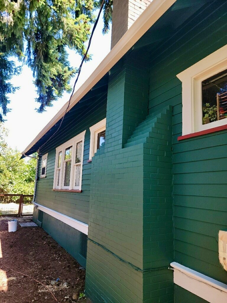 Green house with white trim, freshly painted by Artisan Painting and Remodeling.