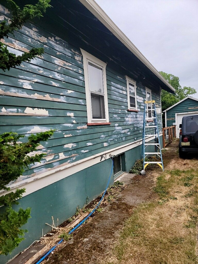 House exterior with peeling paint, being prepped for painting by a professional painter.