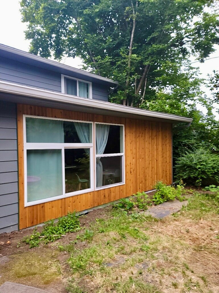 Newly remodeled side of a house with a large window.